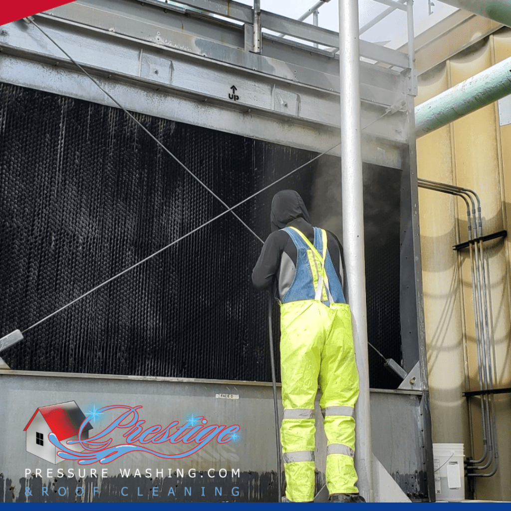 Action shot of Prestige Pressure Washing crew performing cooling tower descaling in Dayton, Ohio — technicians cleaning tower panels