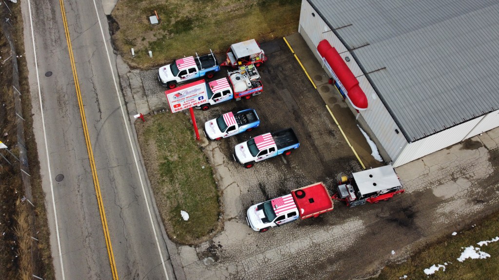 Five Trucks, and Two Trailers Parked in front of The Prestige Pressure Washing Store Front.